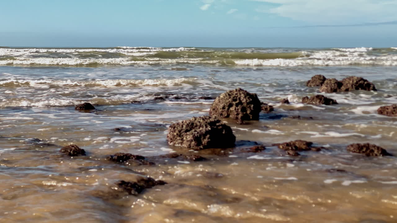 Le rocce sommerse della barriera corallina infrangono le onde in arrivo a Costa Ballena, aggiungendo potenza e consistenza alla superficie increspata dell'acqua marrone.
