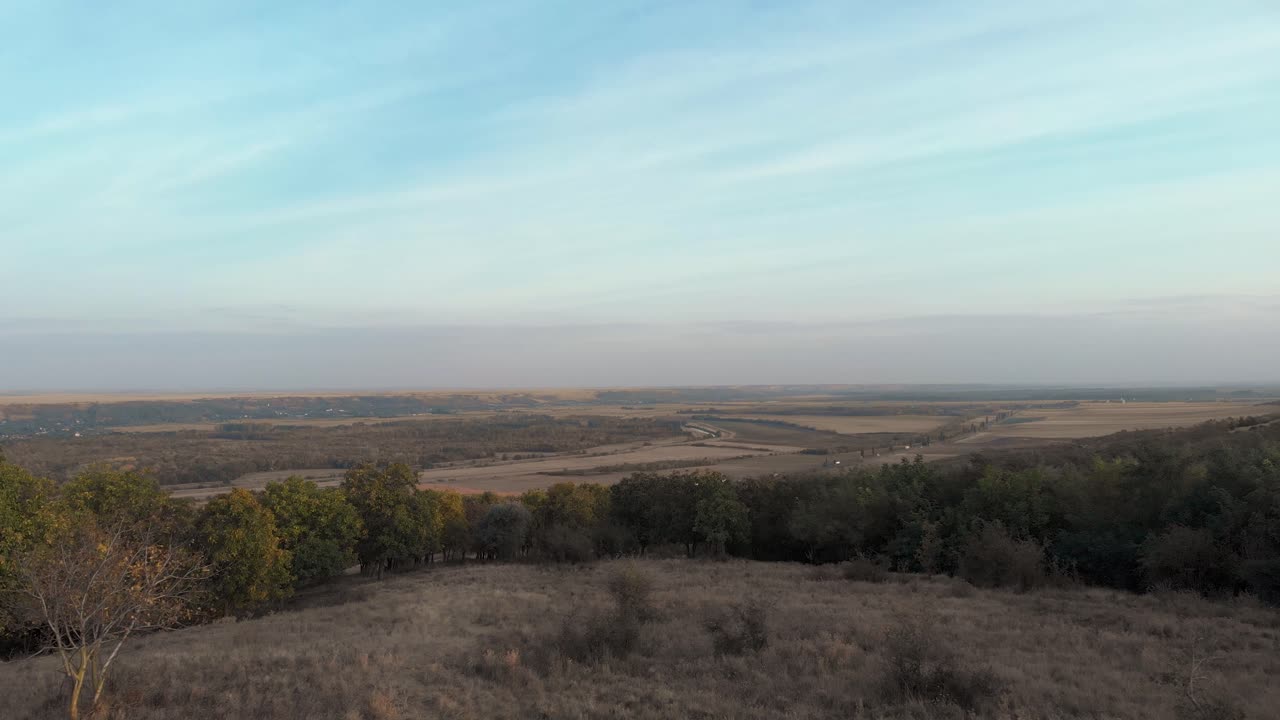 exuberantes bosques verdes en la colina con vistas a vastas tierras de cultivo y camiones en la carretera