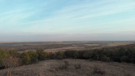 Lush-Green-Woods-At-The-Hill-With-A-View-Of-Vast-Farmland-And-Trucks-On-The-Road