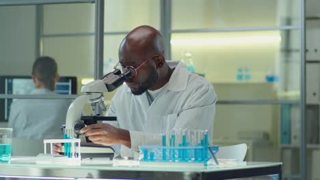 african american scientist working with microscope in lab