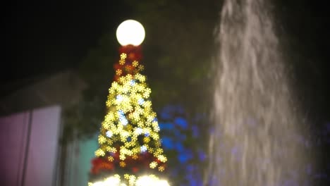 árbol de navidad parpadeando al lado de la fuente.