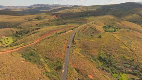 Aerial-drone-view-of-van-car-driving-on-asphalt-road-in-Madagascar-countryside-on-sunny-day