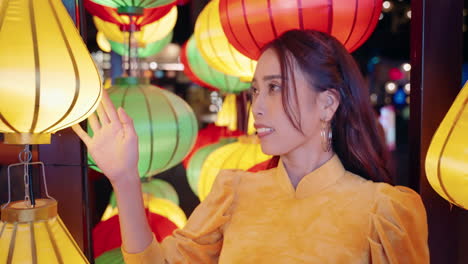 Mujer-De-Amarillo-Ao-Dai-Admira-Coloridas-Linternas-Por-La-Noche-En-Hoi-An,-Vietnam,-Primer-Plano