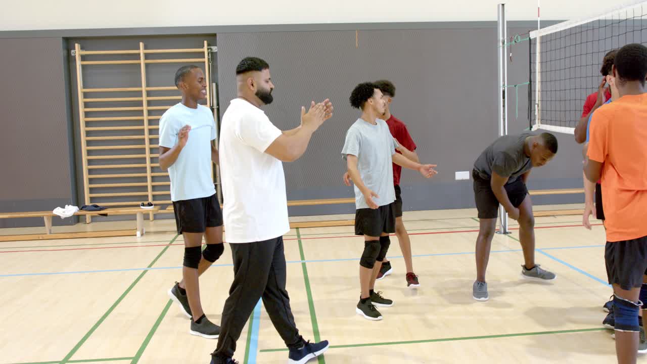 Ein diverses Team betritt den Platz neben dem Netz, skandiert motivierende Parolen und klatscht zur Ermutigung.
