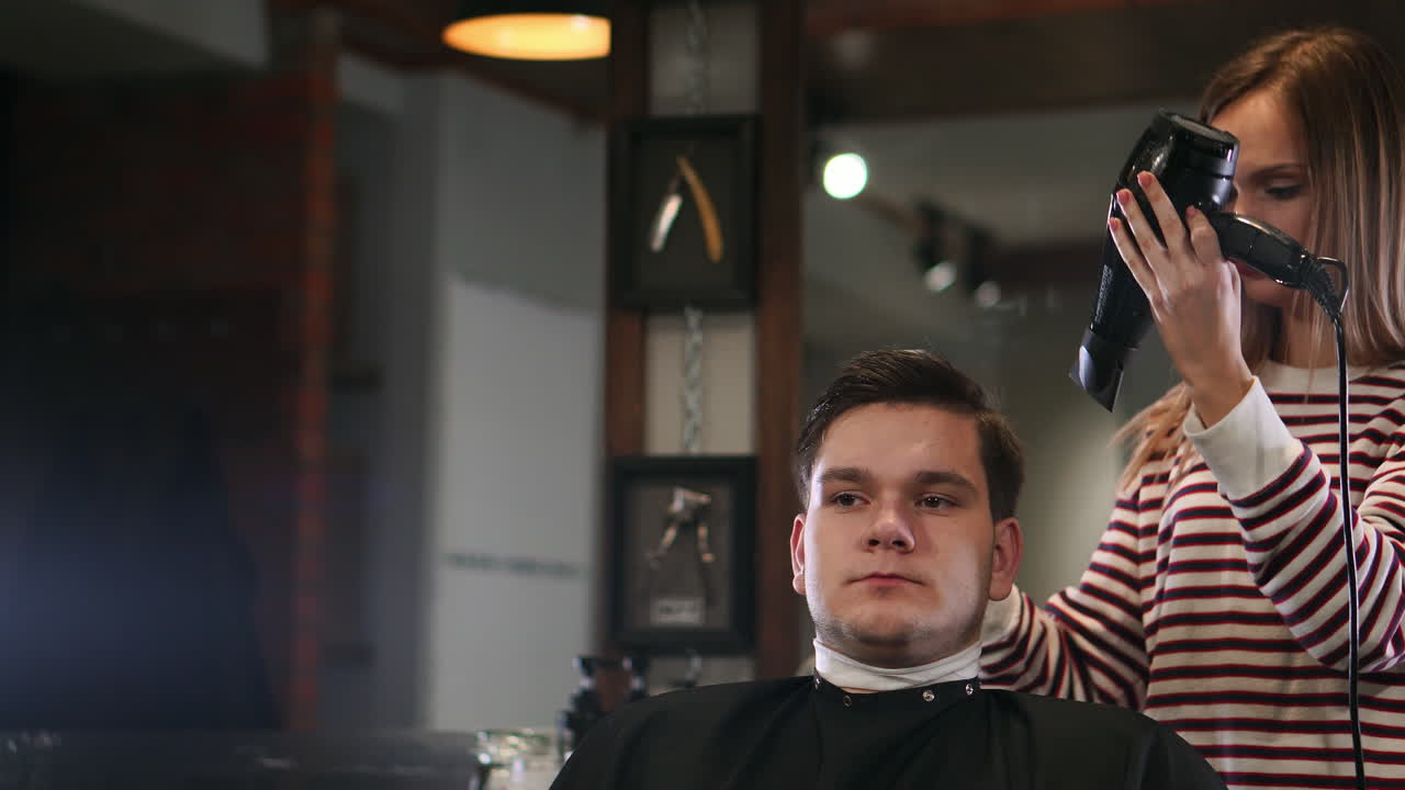 peinado masculino en el salón. hombre secando el cabello en la barbería. barbero peinando el cabello con secador. terminar la peluquería. secador de cabello hombre en la barbería