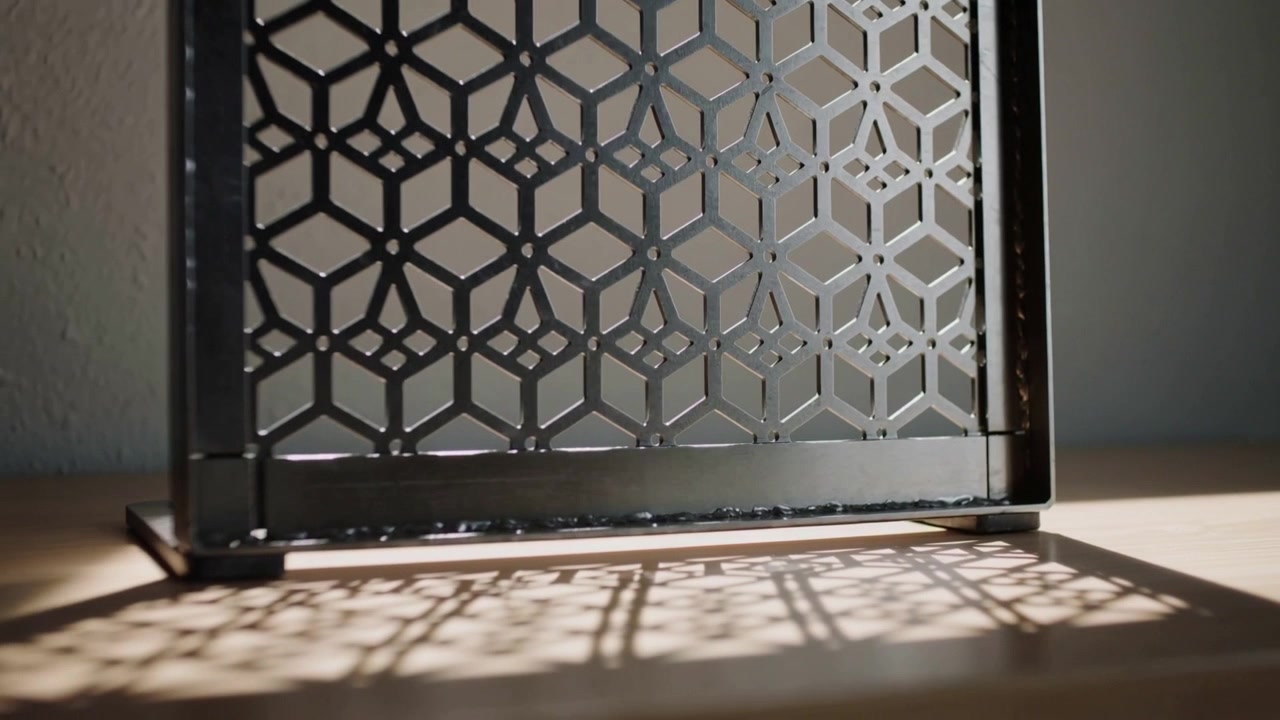 Telecamera panoramica che rivela un pannello metallico che proietta un'ombra geometrica crescente su un tavolo, mostrando i rivetti.