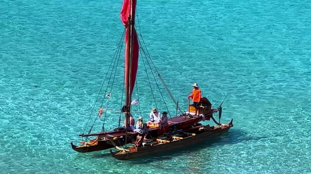 관광객들은 맑은 바닷물에서 전통적인 하와이 범선을 타고 여행을 떠납니다.