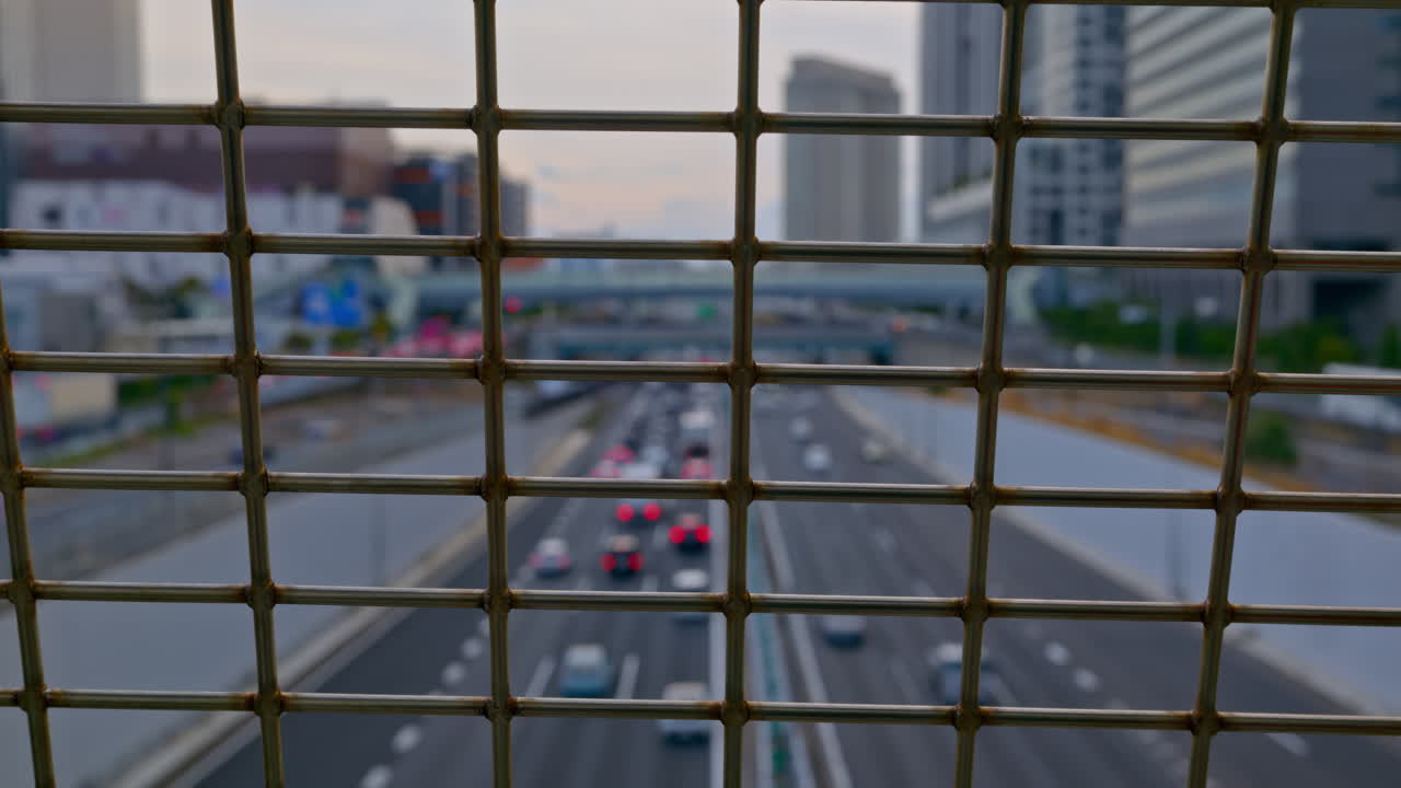Close up of a fence with a blurred view of cars moving on the roads of Daiba, Japan in daylight