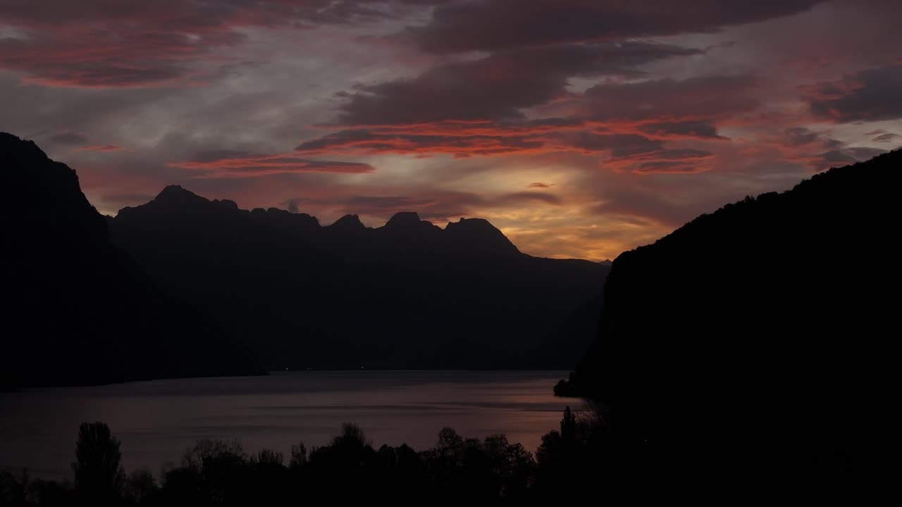 As dusk transitions to night, soft evening hues paint the surface of Lake Walensee, Switzerland, creating a serene and captivating atmosphere that envelops the landscape.