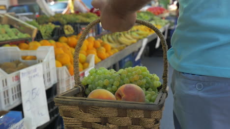 Man-with-basket-of-grapes-and-peaches-on-fruit-market