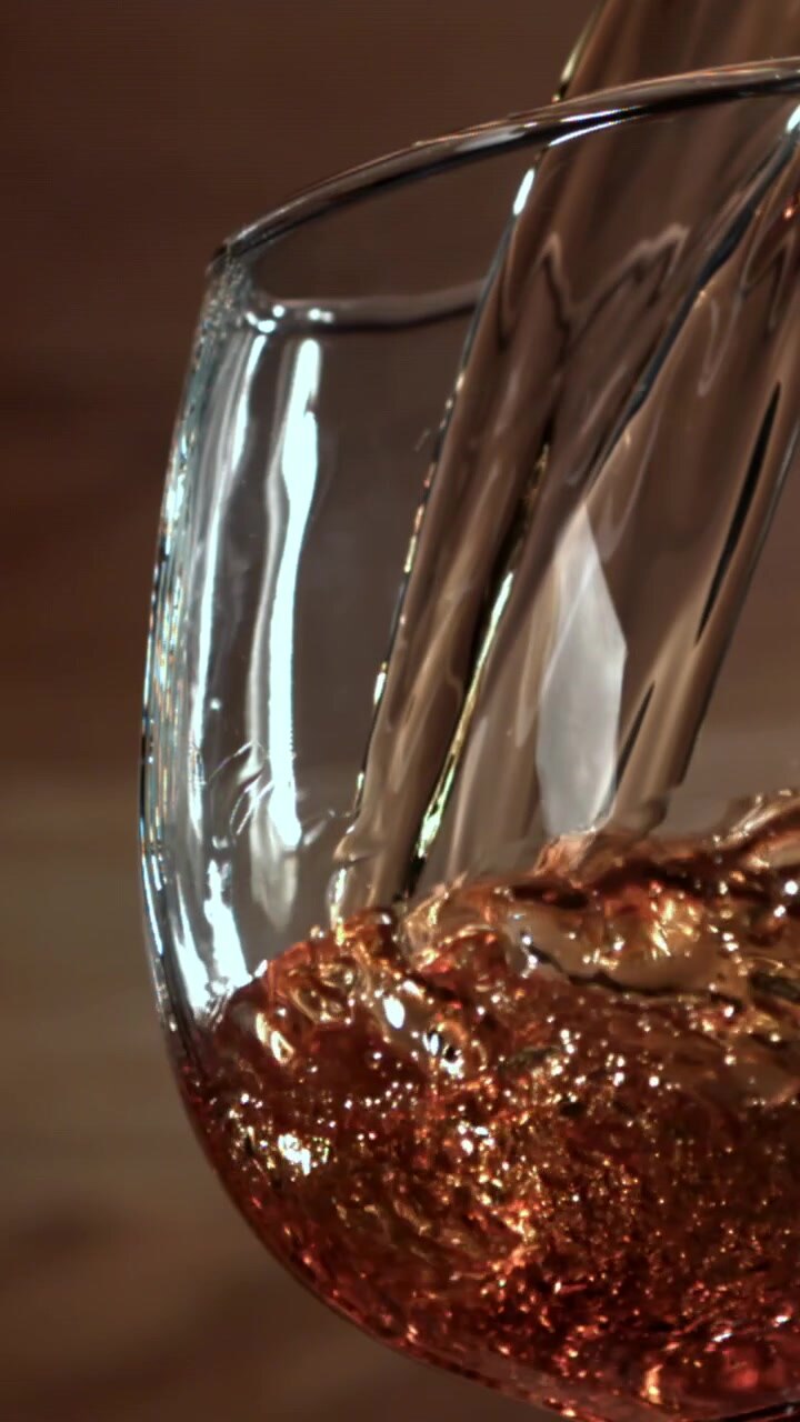 Slow Motion Pour of Golden Amber Liquid into a Glass