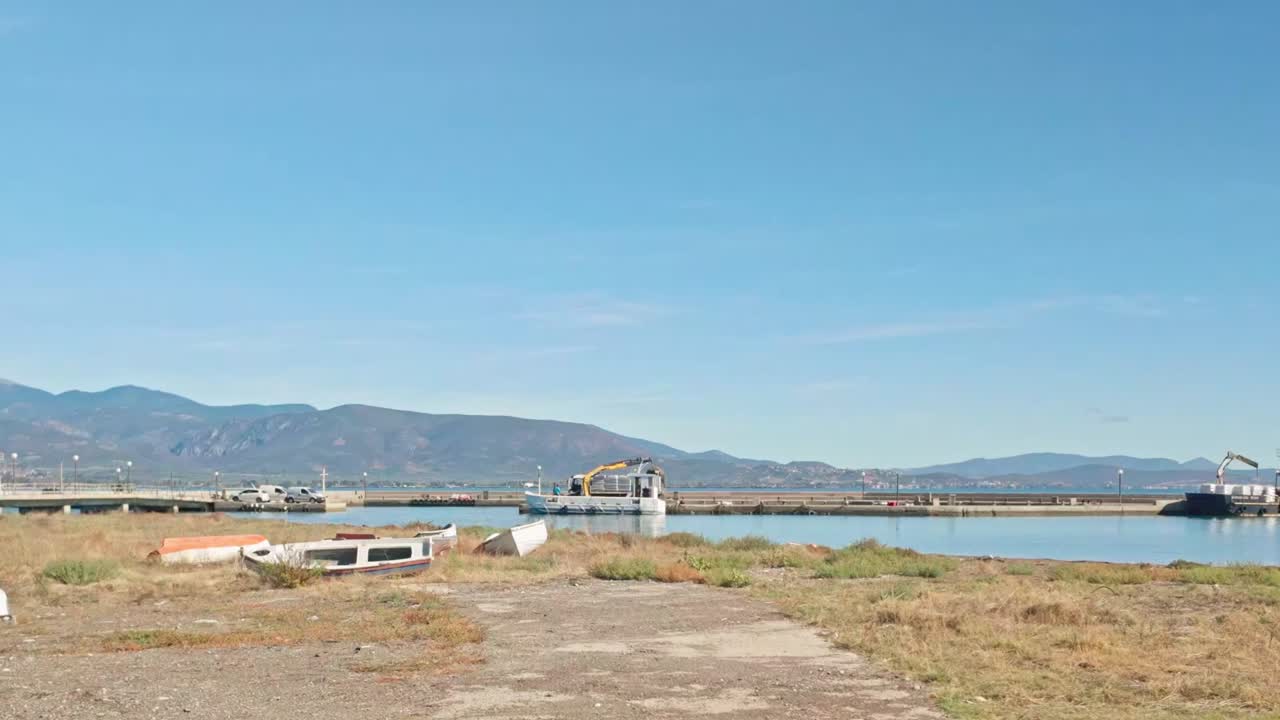 Loading cargo by crane onto coastal sea barges on Greek harbour