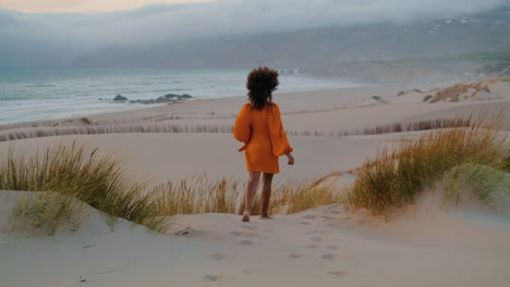 Woman-going-down-hill-waving-hand-summer-evening.-Girl-relaxing-on-seashore.