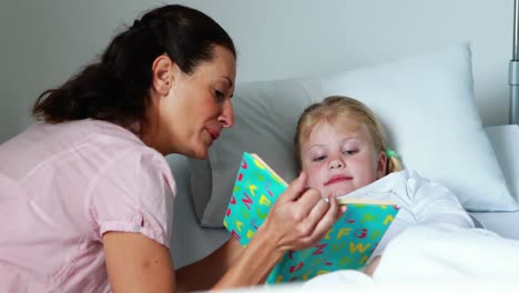 Niña-En-La-Cama-Leyendo-Un-Libro-Con-Su-Madre