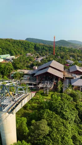 vertical aerial view of the longest three-rope cable car in phu quoc island, vietnam, gliding over lush green forests and scenic landscapes.