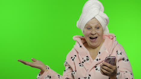 abuela anciana en bata de baño. anciana con teléfono inteligente apuntando a algo