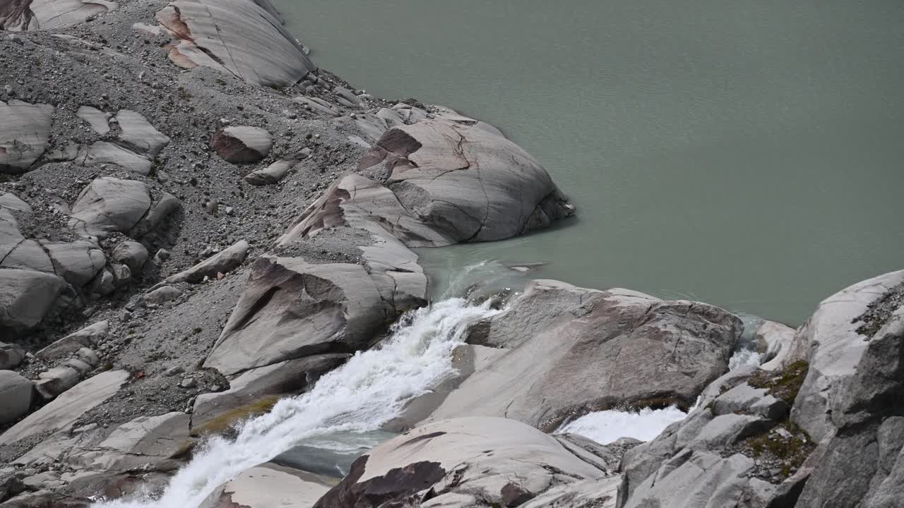 The Rhone leaves a small lake and flows in the rocks, top of the alps, Wallis, Switzerland