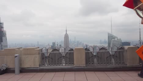 back of male in raincoat walking on top of the rock observation deck, manhattan new york cityscape view