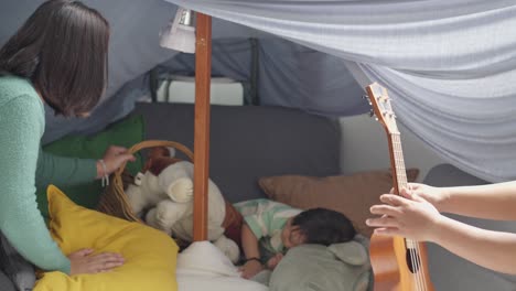 asian young father and mother playing with their daughter in a diy tent at home