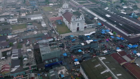 wide slow aerial flyover around the central square in san juan ostuncalco, showing the market and the cathedral in the background