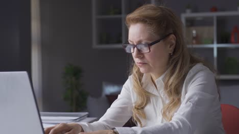 Senior-elderly-business-woman-works-from-computer-at-home-and-wears-her-glasses.