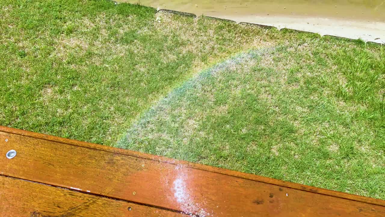 el arco iris aparece sobre la hierba y la cubierta de madera
