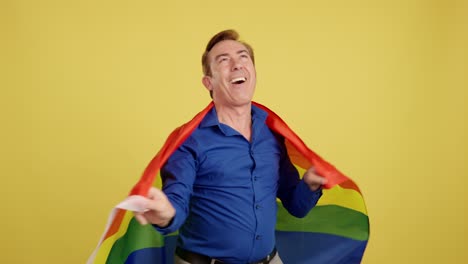 happy man wrapped in rainbow flag against yellow background