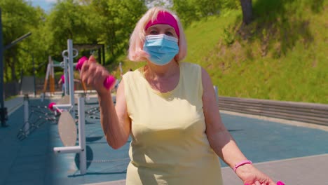 Senior-woman-grandmother-doing-training-weightlifting-exercising-with-dumbbells-on-park-playground