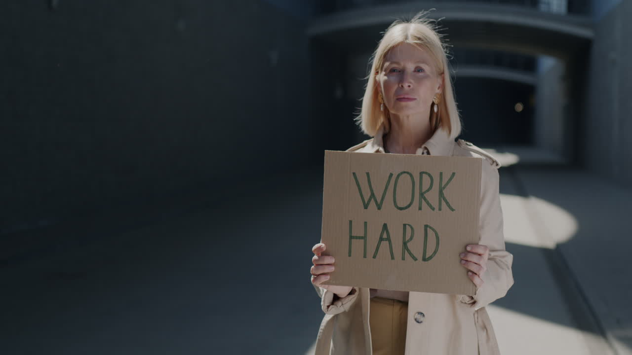 Frau hält ein Schild mit der Aufschrift „Arbeit“ in städtischer Umgebung