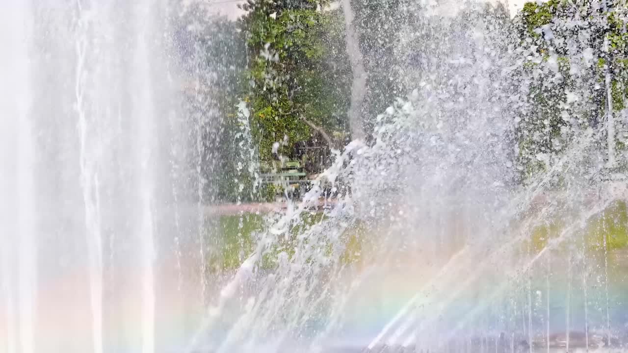 A close-up view of a fountain's water jets creating a vivid rainbow effect.