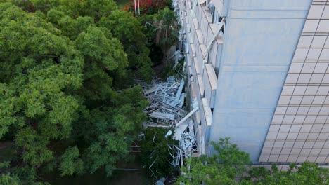 circular drone close-up reveals debris on ground next to damaged building and surrounding vegetation in tel aviv