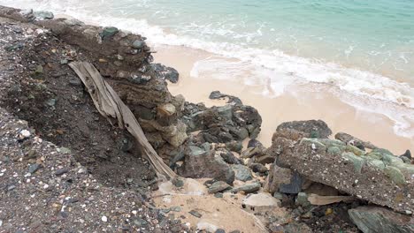 ocean sea wall and road corrosion, collapsed due to impacts of rising tides, climate change, with waves gentle washing onto the beach