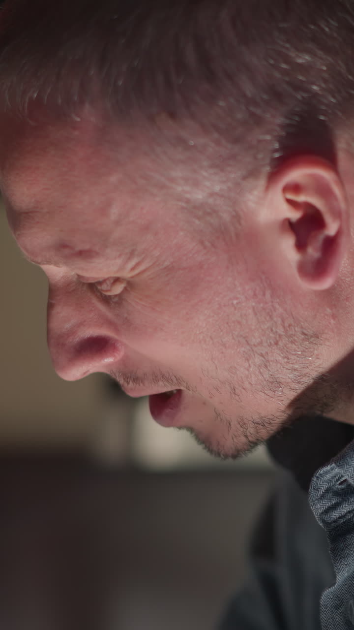 Close-up of a man in a blue shirt, appearing to play a piano with focus and concentration. The background is blurred, emphasizing the subject and creating a mood of creativity and musical engagement