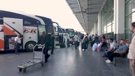 busy bus station: passengers boarding and waiting for buses