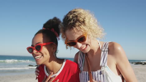 Two-young-adult-female-friends-having-fun-at-the-beach-4k