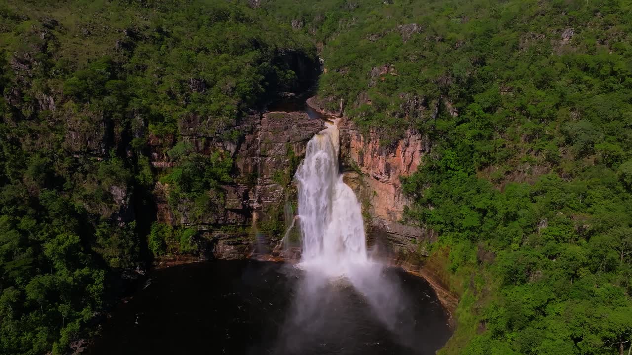 Cascading down into the Rio Preto river, Cachoeira dos Saltos waterfall is surrounded by lush vegetation in Chapada dos Veadeiros National Park, Goiás, Brazil