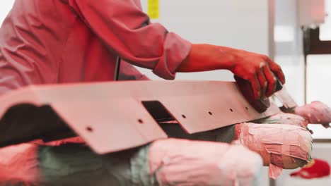 African-American-male-car-mechanic-using-a-grinder-on-a-piece-of-a-car