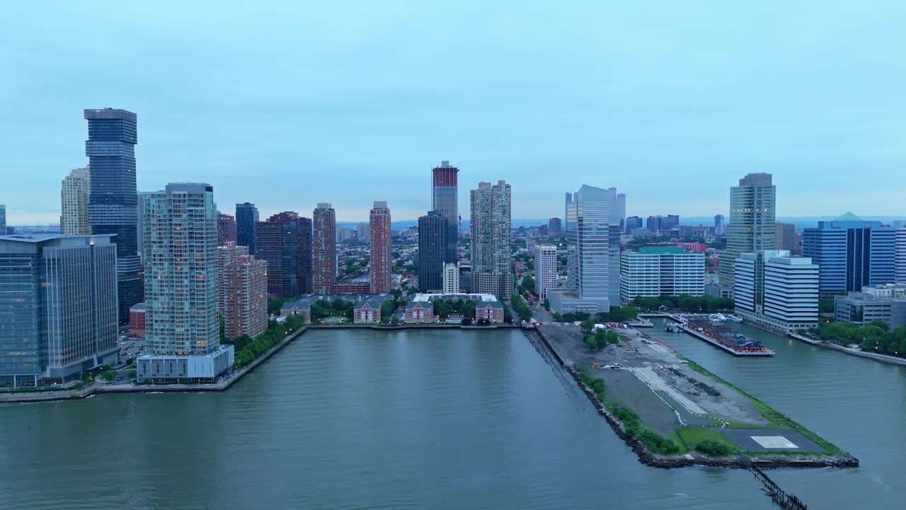 Jersey City skyline along Hudson River, modern high-rise buildings and waterfront on cloudy, overcast day, New Jersey, USA