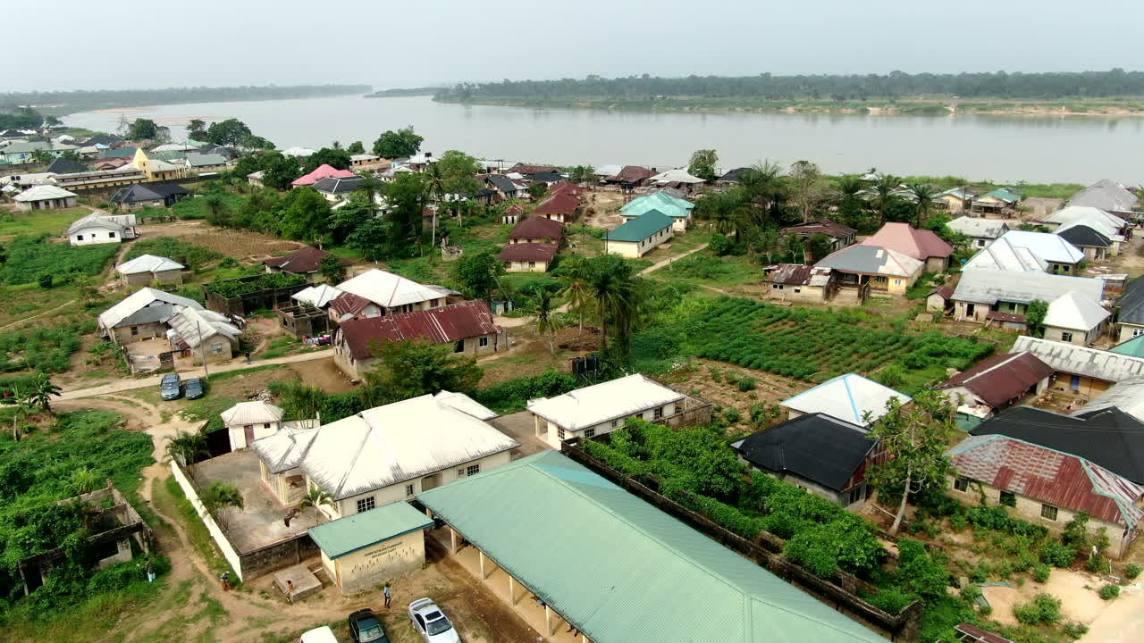 A hawk or eagle flies through the aerial view of the Odi Community along the Nun River
