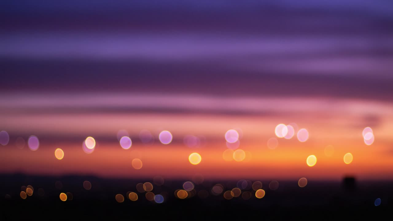 A Beautiful Transition of Colors in the Sky During Dusk, Displaying Soft Blurred City Lights Against a Vibrant Sunset Background Captured in Two Frames