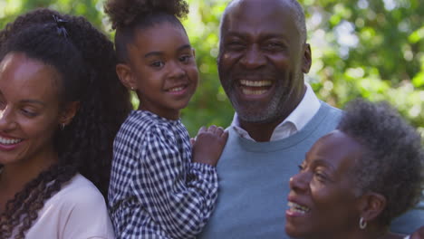 Portrait-Of-Smiling-Multi-Generation-Family-Enjoying-Walk-In-Countryside-Together