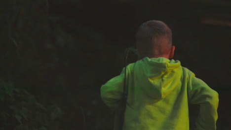 child walks alone in evening woods. little boy plays in high grass in nature park on vacation. active kid explores wild forest walking in evening