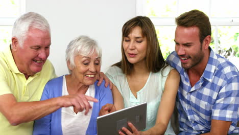 dos generaciones sentadas en un sofá y mirando una tableta