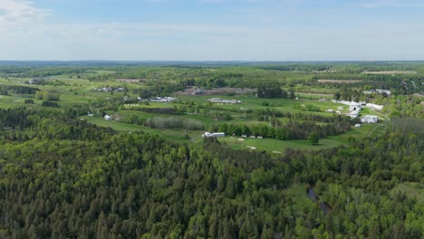 golf course by green forest and distant horizon in canada, aerial push-in