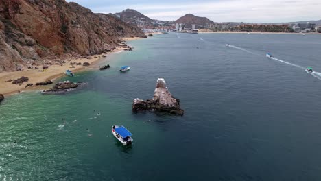 pelican rock, touristic attraction at cabo san lucas, tour boats on blue sea, aerial orbit view