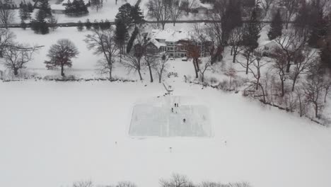 aerial, family and friends ice skating in backyard pond ice rink