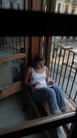 woman studying on a balcony on a rainy day