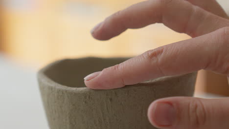 dexterous fingers sculpt a clay cup's delicate form, close-up glimpse into an artisan's magical creation