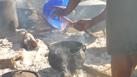 lady cooking in big black pots at a traditional african wedding