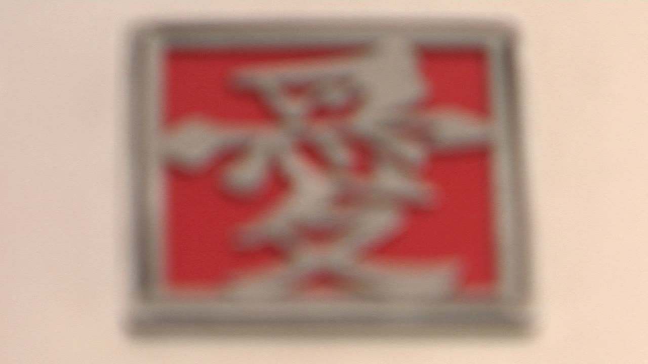 아시아 문자가 있는 빨간색과 은색 사각형이 분홍색 표면에 놓여 있습니다.